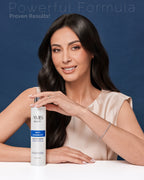 Smiling woman with long, wavy dark hair holding a bottle of anti-dandruff shampoo.