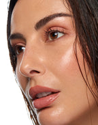 Close-up of a woman's face highlighting glowing, radiant skin and a dewy complexion.
