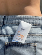 Tube of Krem dielli SPF 50+ tucked into the back pocket of light blue denim jeans.