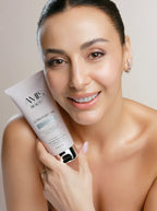 Smiling woman with bare shoulders holding a tube of Ultra Purifying Cleansing Gel close to her face.