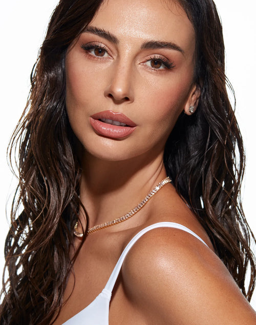 Portrait of a woman with glowing skin and dark hair pulled back, looking to the side.