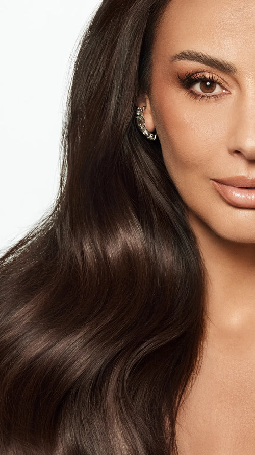 Close-up portrait showcasing a woman with very long, smooth, and glossy dark brown wavy hair.