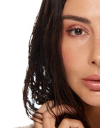 Close-up crop of a woman's face, focusing on her glowing skin and dark wavy hair.