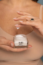 Close-up of a woman's hands holding an open jar of Anti-Age Lifting cream and dipping a finger into the product.