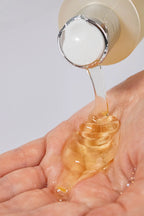 Close-up of golden Curly Crush Conditioner being poured into a person's hand.